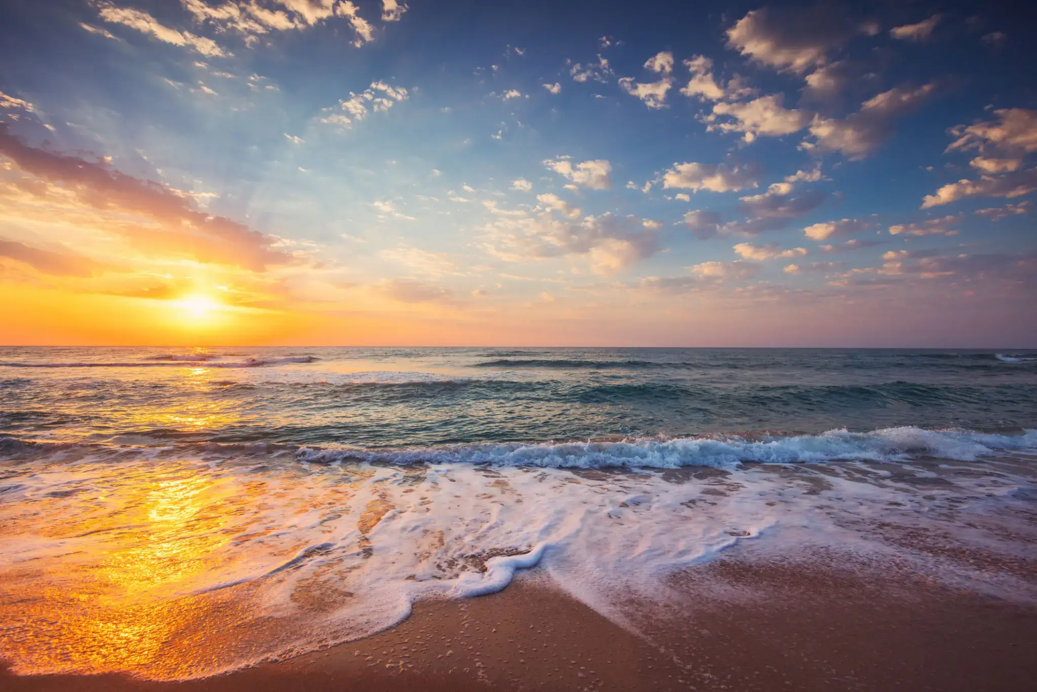 Sunset over a serene beach with gentle waves.