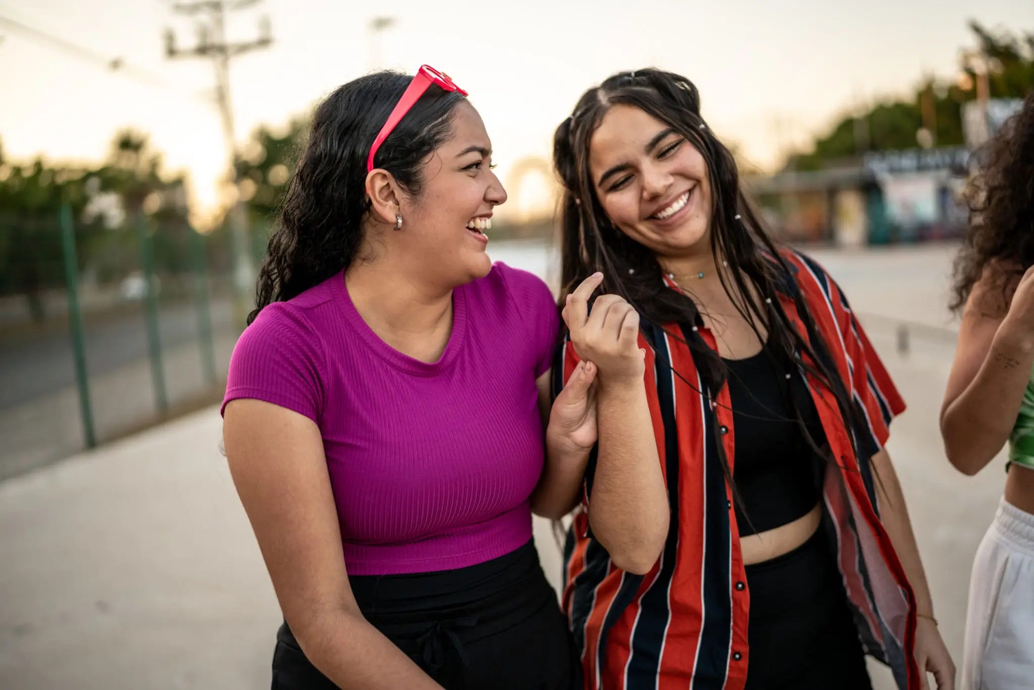 Two young women smiling and enjoying each other's company outdoors.