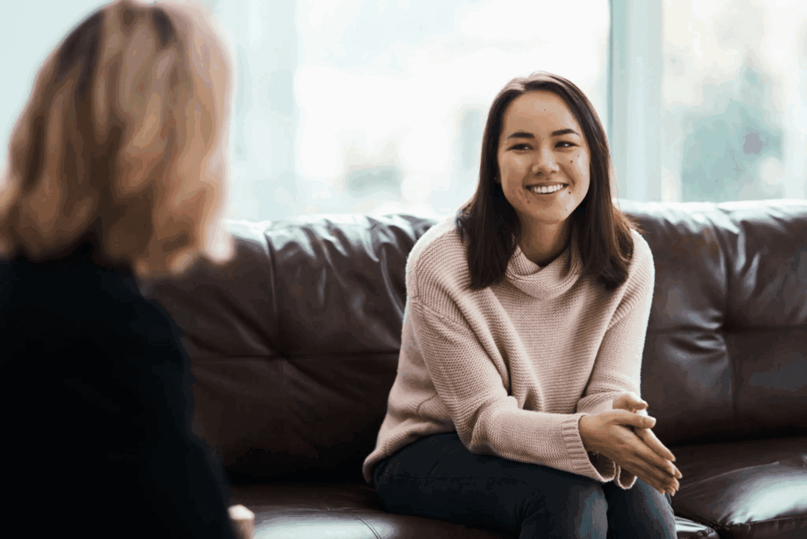 Two women engaged in a friendly conversation on a couch.