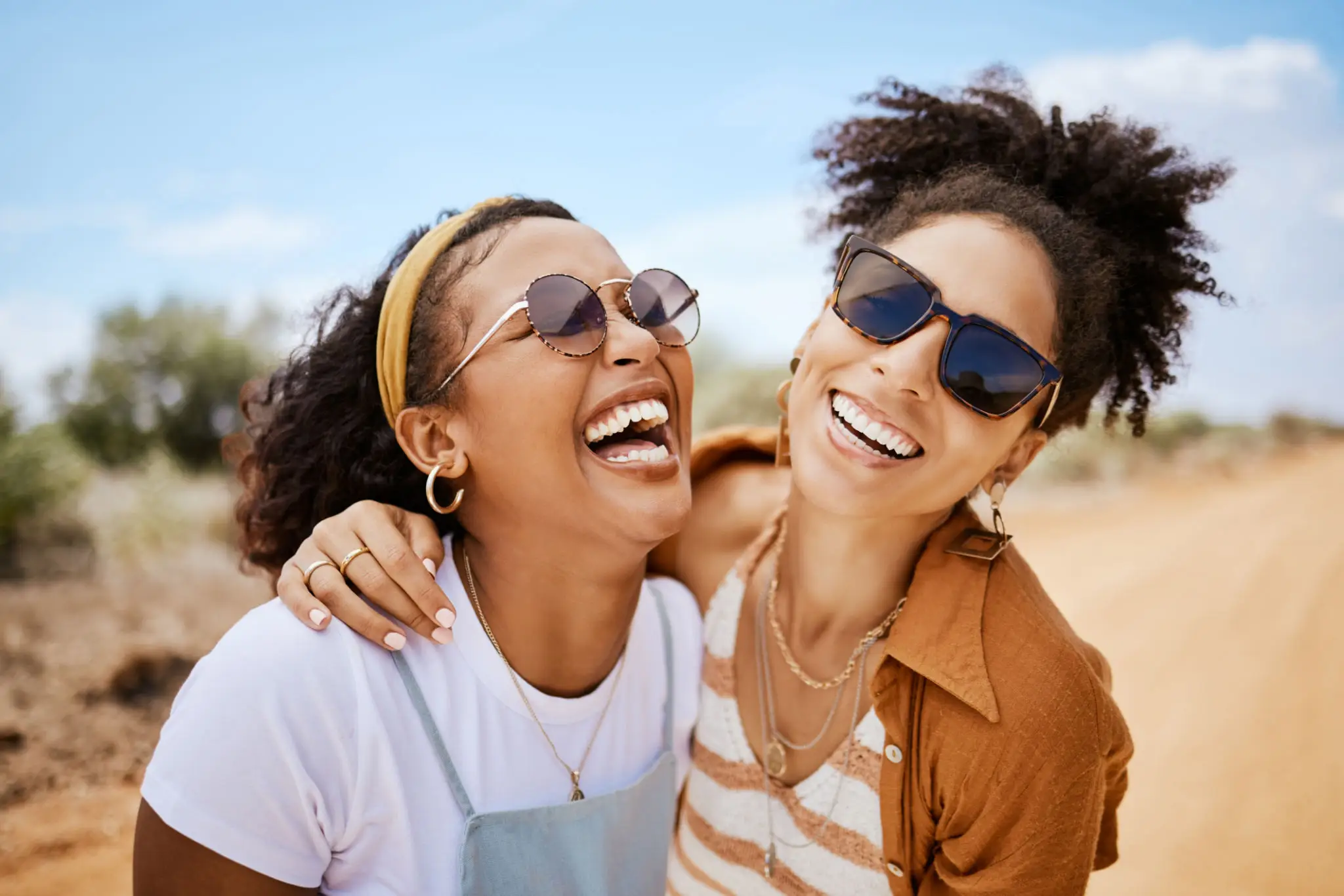 Two women laughing and enjoying a sunny day outdoors.