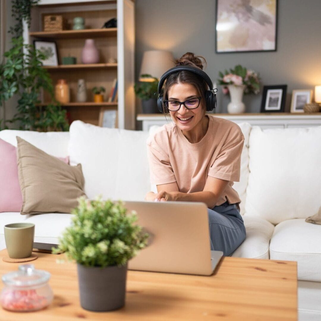 A woman smiling while working on a laptop at home.