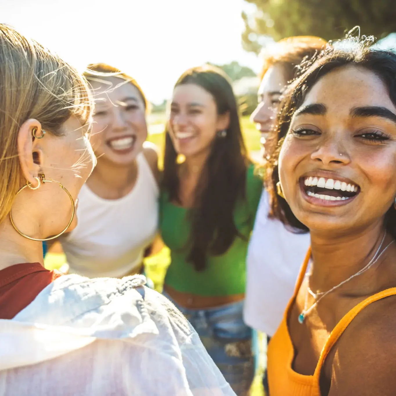A group of diverse young women laughing together outdoors.