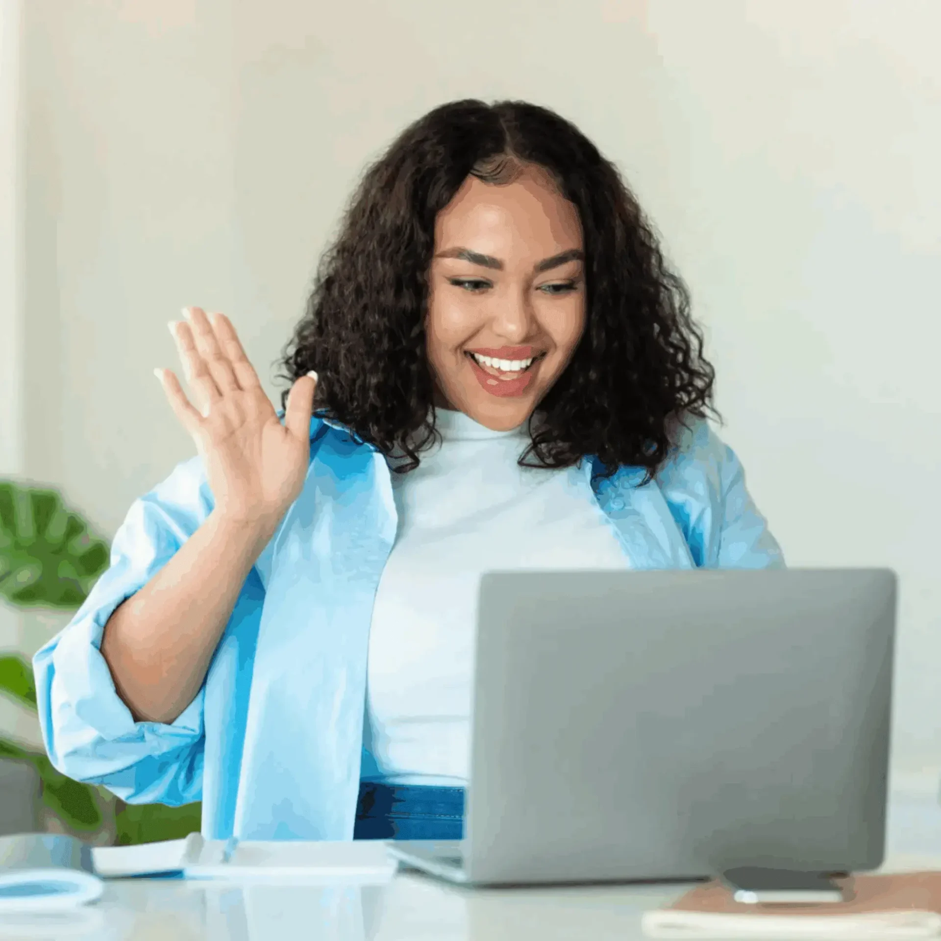 Woman waving at her laptop during a video call.